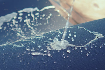 Person pouring water onto a blue surface with visible water droplets.